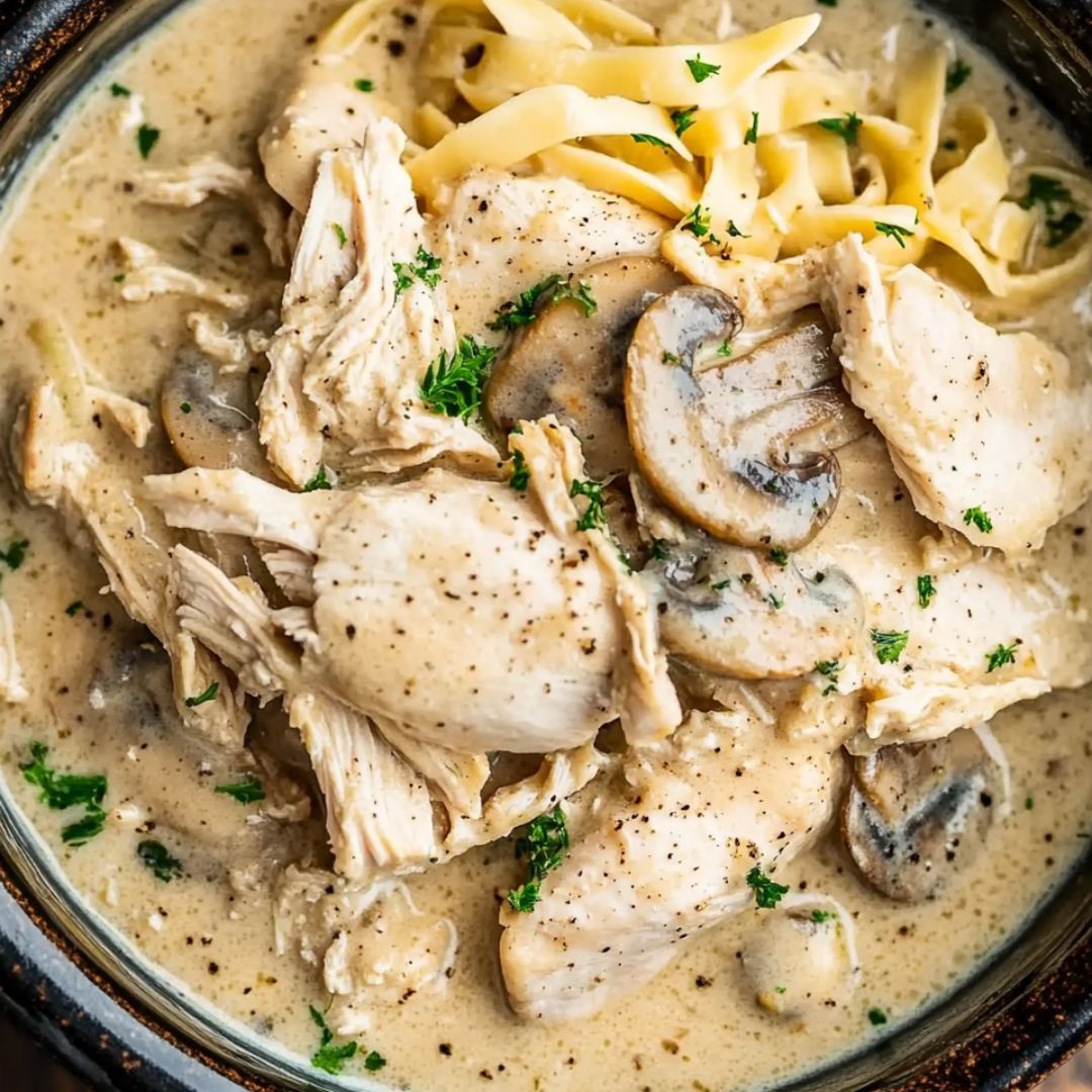 Slow cooker chicken with cream of mushroom soup served over mashed potatoes and garnished with parsley