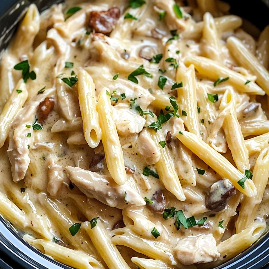 Creamy slow cooker chicken and pasta served in a white bowl, topped with fresh parsley